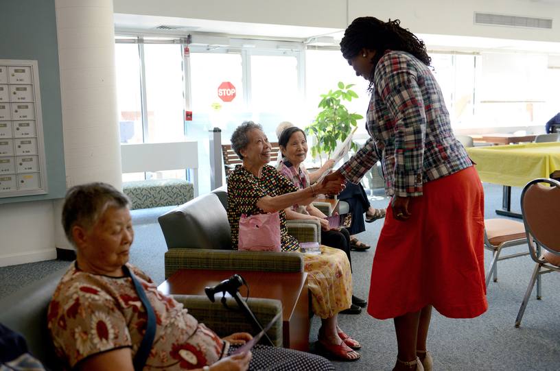 Pressley shaking hands with seated woman while others look on